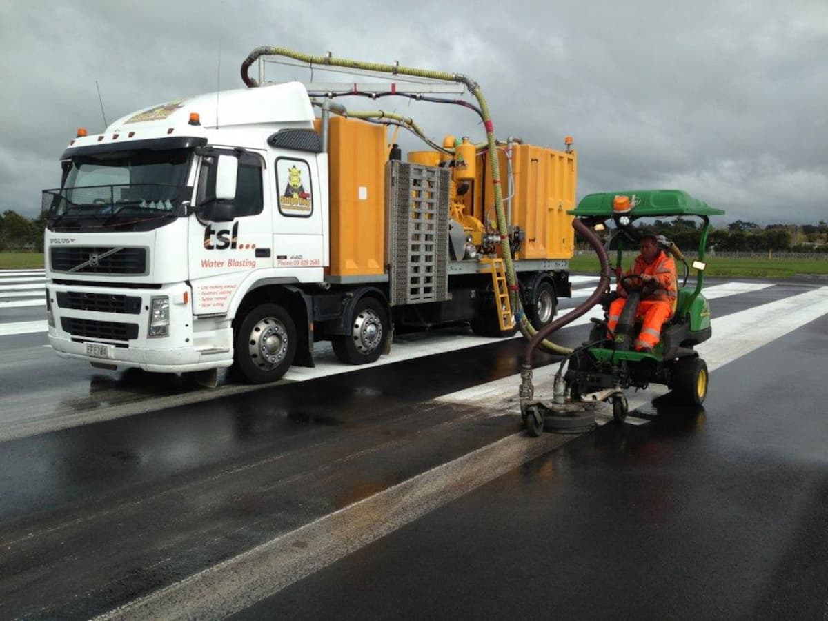 TSL worker removing road marking with water blaster