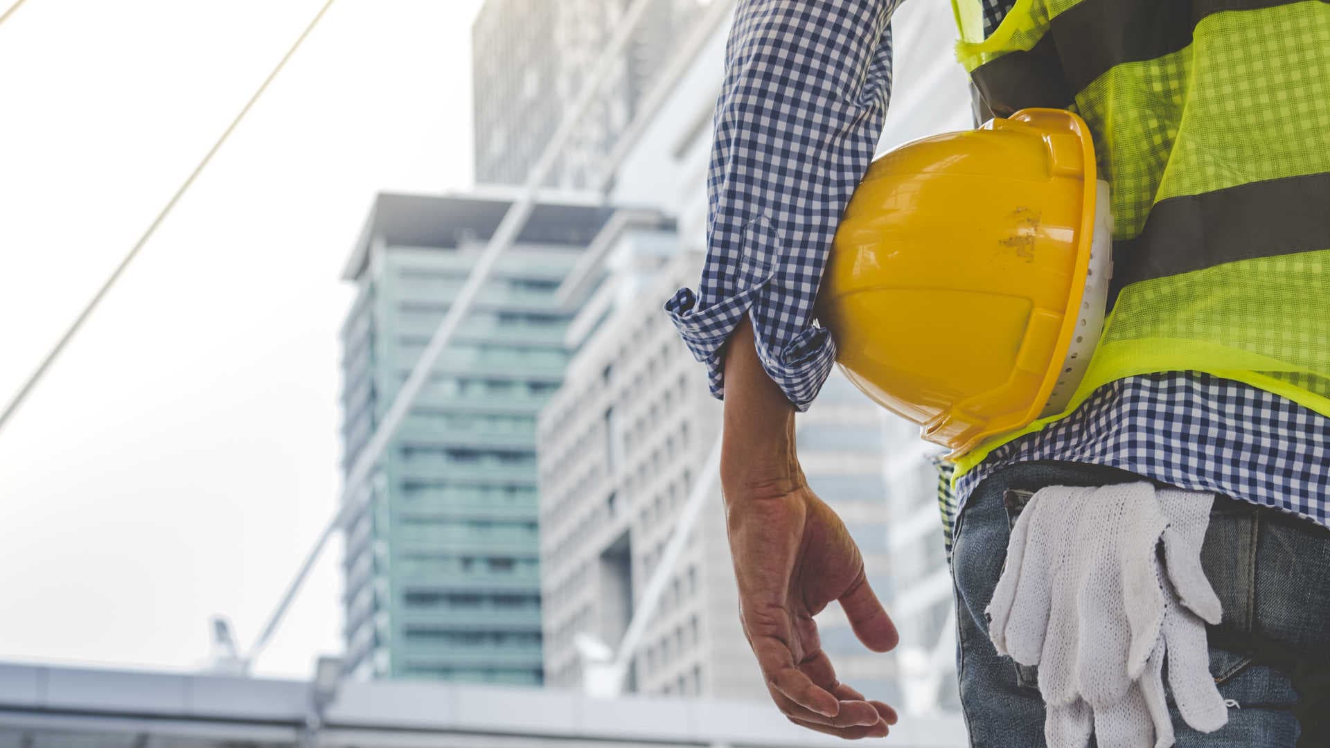 Best civil construction company – Worker overlooking project with helmet in hand