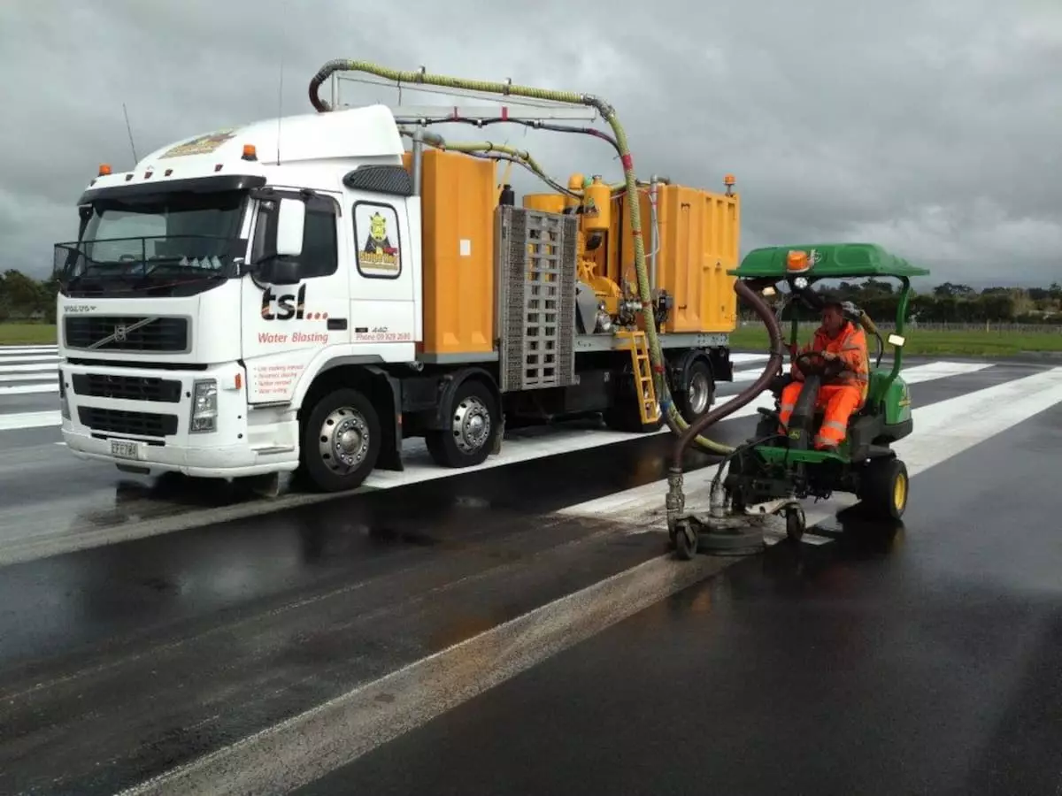 TSL worker removing road marking with water blaster